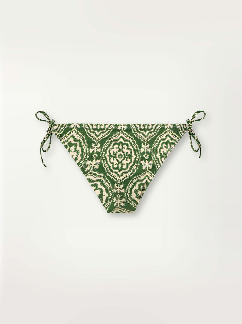 Product shot of the Medallion String Bikini Bottom featuring architectural white patterns on a deep green background.