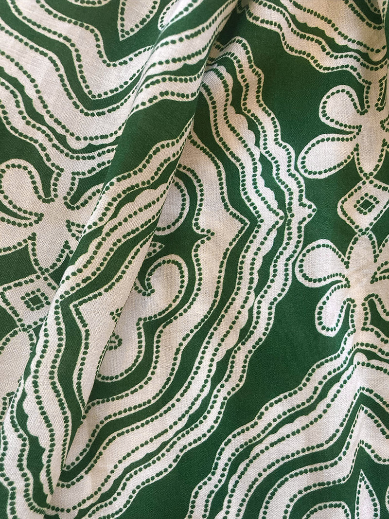 Close up on the fabric of the Medallion Ruched Crop Top featuring architectural white patterns on a deep green background.