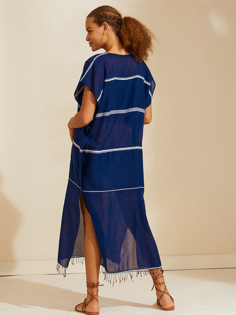 Back view of a woman standing wearing the Nunu classic caftan in navy blue featuring white stripes and graphic lines.