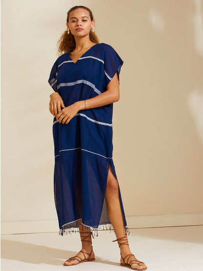 Woman standing wearing the Nunu classic caftan in navy blue featuring white stripes and graphic lines.