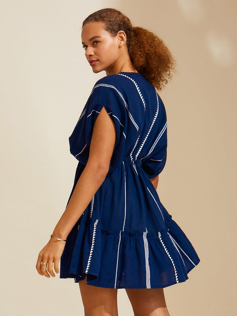 Side view of the back of a woman wearing the Nunu short Plunge Neck in Navy blue with white stripes and graphic lines.