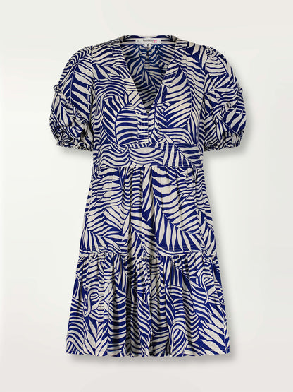 Product shot of the Palm Leaf Flutter Sleve Mini Dress featuring palm tree patterns on a rich blue background.