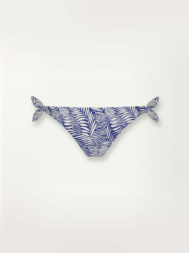 Product shot of the Palm Leaf Side Tie Bikini Bottom featuring palm tree patterns on a rich blue background.