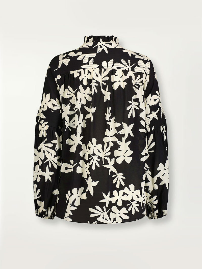 Product shot of the back of the Sea Floral Ruffle Blouse in Black featuring white allover floral print.