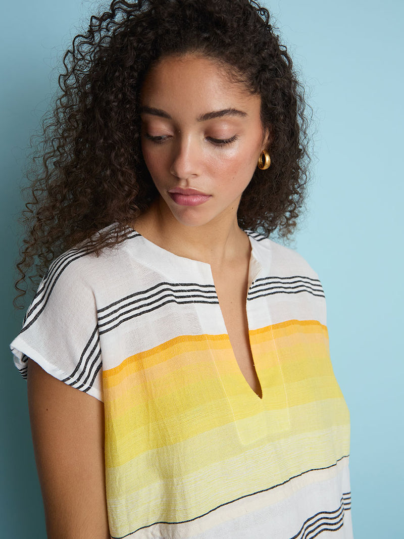 A close up view of a woman standing wearing the Zena Tunic Dress in yellow featuring black stripes and yellow degrade.