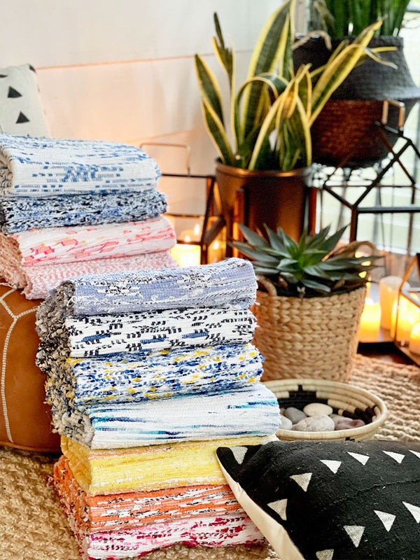 Several multi colored handwoven rugs folded and stacked on each other.